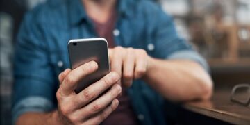 Closeup shot of an unrecognizable designer using a cellphone in an office